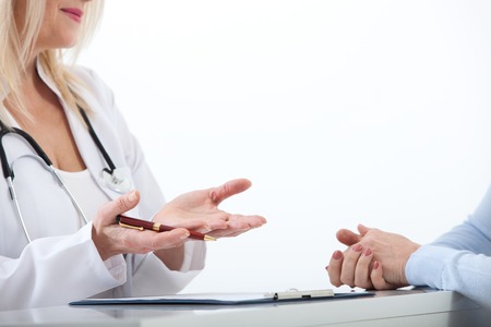Doctor and patient are discussing something, just hands at the table close upの写真素材
