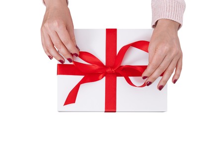 Gift box isolated on white background. Woman holding presents and tying a red ribbon on a gift boxの写真素材