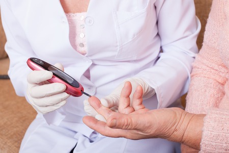 Nurse takes test for sugar in blood of elderly woman at home.の写真素材