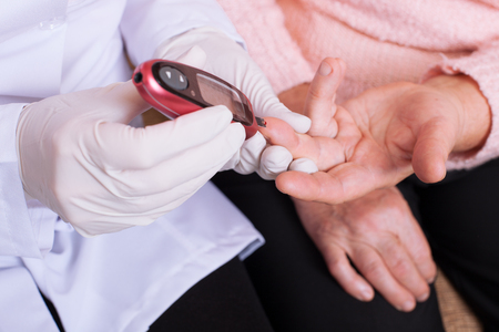 Nurse takes test for sugar in blood of elderly woman at home.の写真素材