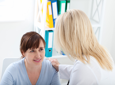 Female patient being reassured by doctor in hospital.の写真素材
