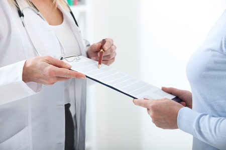 Female doctor holding application form while consulting patient at hospitalの写真素材