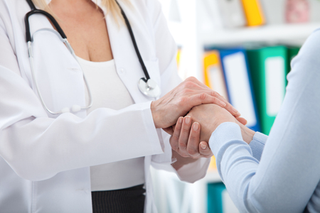 Hand of doctor reassuring her female patient. Medical ethics and trust concept. Handshake, hands closeupの写真素材
