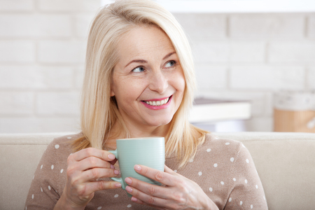 Portrait of happy blonde with mug in handsの写真素材