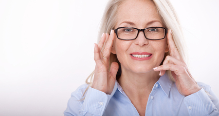 Middle aged business woman with eyeglasses in blue shirt isolated on white backgroundの写真素材