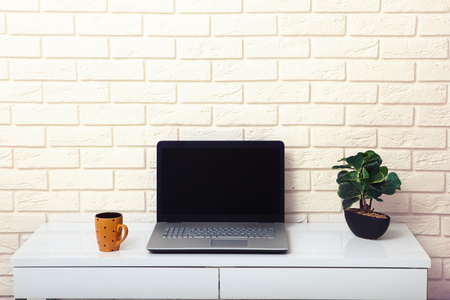 White table near the white wall. Empty workplace in the room. White background.の写真素材
