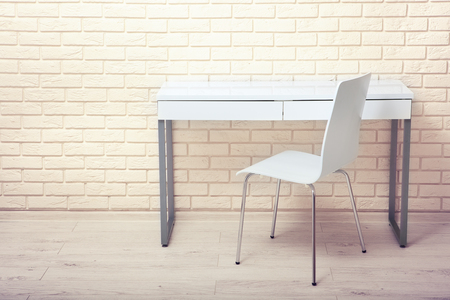 White table near the white wall. Empty workplace in the room. White background.の写真素材