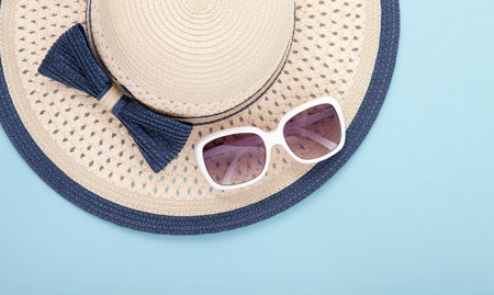 Summer hat with ribbon and sunglasses isolated on colorful background. Top view and copy space.