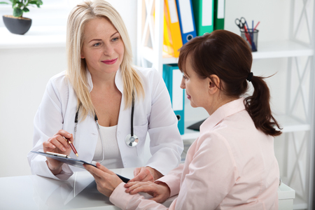 Female doctor holding application form while consulting patientの写真素材