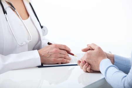 Doctor and patient are discussing something, just hands at the table close upの写真素材