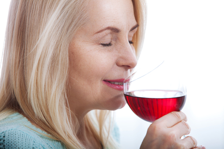 Happy blonde drinking red wine with eyes closed.の写真素材