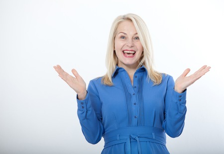 Portrait of happy middle aged woman. Surprised happy woman looking with her mouth open and holding her arms out in excitement. Isolated over white backgroundの写真素材
