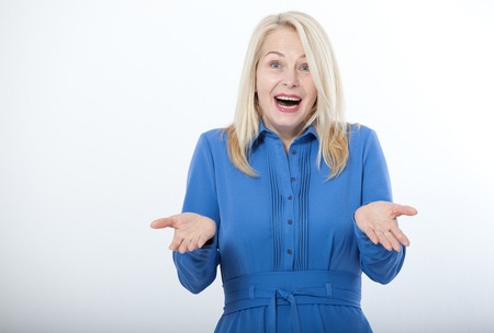 Portrait of happy middle aged woman. Surprised happy woman looking with her mouth open and holding her arms out in excitement. Isolated over white backgroundの写真素材