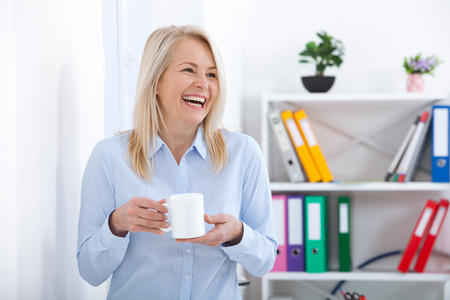 Smiling middle aged businessman with cup of coffee in the office. Coffee break.の写真素材
