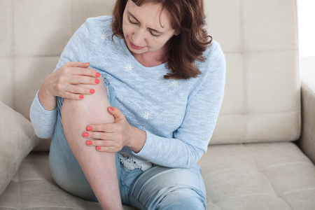 Woman suffering from pain in knee, close upの写真素材