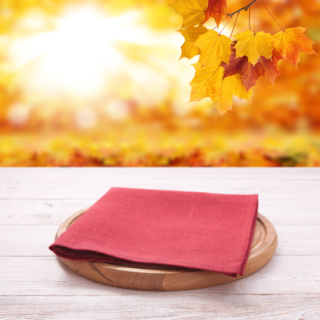 Pizza board with towel on wooden desk. Autumn background. Top view mock up. Selective focus.の写真素材