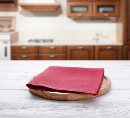 Empty pizza board with tablecloth on the table and kitchen interior blurred backgroundの写真素材