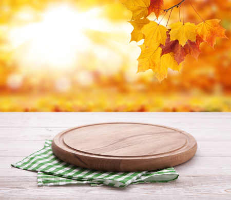 Pizza board with towel on wooden desk. Autumn background. Top view mock up. Selective focus.の写真素材