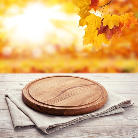 Autumn landscape and pizza board with napkin on wooden table.の写真素材