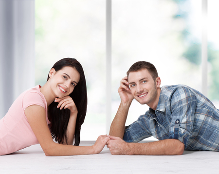 Happy young couple, lying on the floor, look at each other and dream of furniture for a new apartment. Mock upの写真素材