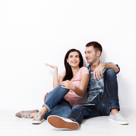 Happy young couple sitting on floor looking up while dreaming their new home and furnishing. Mock upの写真素材