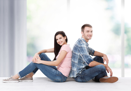 Happy young couple sitting on floor looking up while dreaming their new home and furnishing. Mock upの写真素材