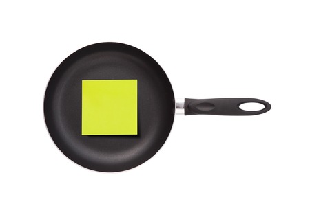 Stick note on frying pan, on white backgroundの写真素材