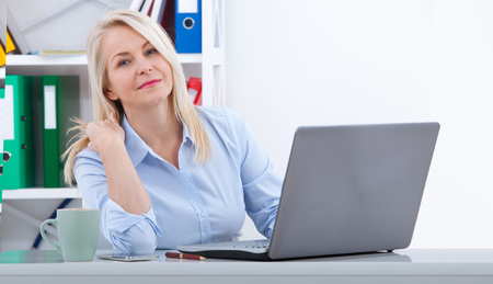 Pretty middle aged business woman working on computer in her officeの写真素材