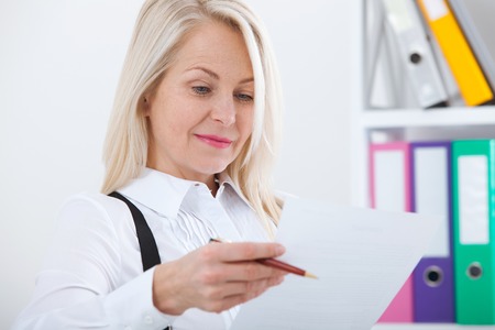 Happy business woman working in office with documentsの写真素材