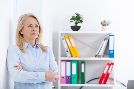 Business woman standing near the wall looking out the window thinking over the strategy.の写真素材