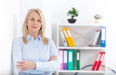 Business woman standing near the wall looking out the window thinking over the strategy.の写真素材