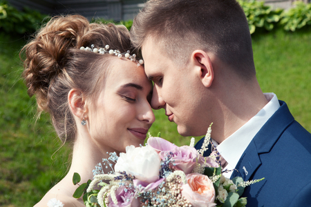 Bride and groom in a park. Kissing couple newlyweds bride and groom at wedding in nature green forest are kissing photo portrait.Wedding Couple Wedding ceremony concept.の写真素材