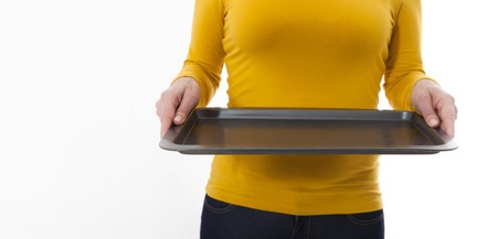 Woman gives empty tray for your advertising products isolated on whiteの写真素材