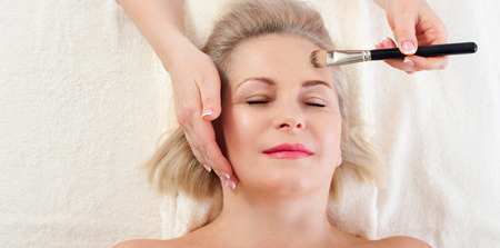 Attractive woman with close eyes taking skin care. Massage face selective focus.の写真素材