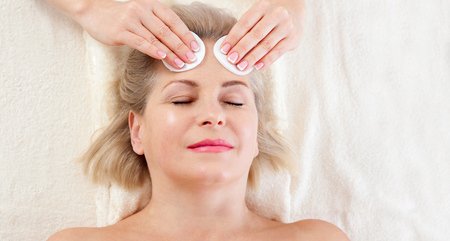 Portrait of beautiful woman in spa environment. middle aged woman doing facial massage in a spa salonの写真素材