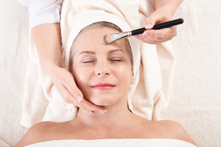 Face massage in spa macro. Attractive woman with close eyes taking skin care.の写真素材
