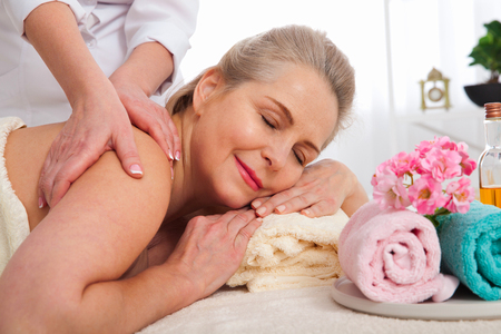 Face massage in spa macro. Attractive woman with close eyes taking skin care.の写真素材