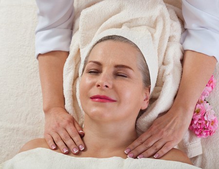 Face massage in spa macro. Attractive woman with close eyes taking skin care.の写真素材