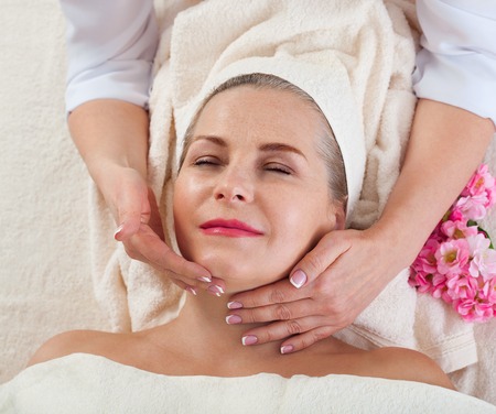 Face massage in spa macro. Attractive woman with close eyes taking skin care.の写真素材