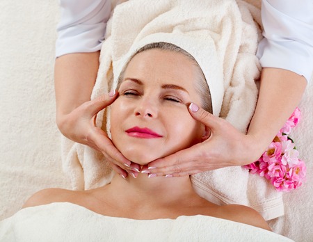 Face massage in spa macro. Attractive woman with close eyes taking skin care.の写真素材