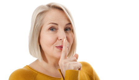 Woman in bright clothes with a finger near her lips isolated on whiteの写真素材