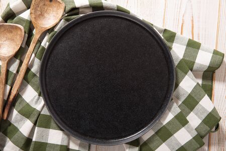 Black plate or tray, or pizza board, with tablecloth on wooden tableの写真素材
