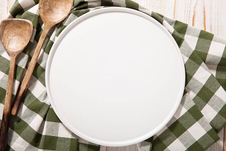 Black plate or tray, or pizza board, with tablecloth on wooden table. Top view mockupの写真素材