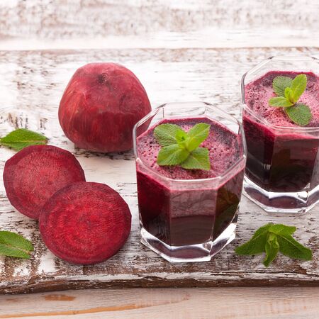 Healthy and healthy detox smoothies or juice from raw beets and spinach in glass bottles on woodenの写真素材