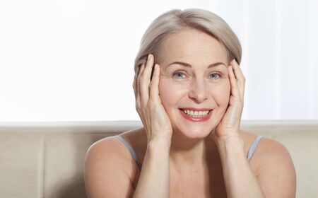 Fifty year old woman is very pleased with her well-groomed face. Plastic surgery collagen injections. Macro face. Selective focus on face. Realistic images with their own imperfections.の写真素材
