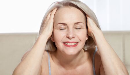 Fifty year old woman is very pleased with her well-groomed face. Plastic surgery collagen injections. Macro face. Selective focus on face. Realistic images with their own imperfections.の写真素材