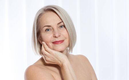Fifty year old woman is very pleased with her well-groomed face. Plastic surgery collagen injections. Macro face. Selective focus on face. Realistic images with their own imperfections.の写真素材