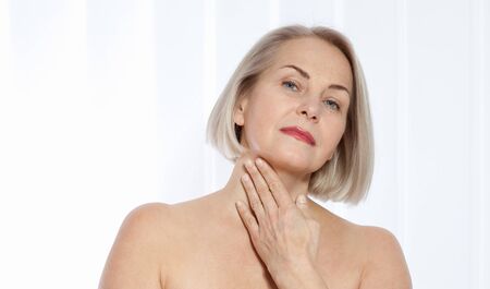 Beautiful middle-aged blonde woman shows off her perfectly well-groomed face. Plastic surgery collagen injections. Macro face. Selective focus on face. Realistic images with their own imperfections.の写真素材