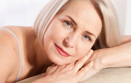 Beautiful middle-aged blonde woman shows off her perfectly well-groomed face. Plastic surgery collagen injections. Macro face. Selective focus on face. Realistic images with their own imperfections.の写真素材