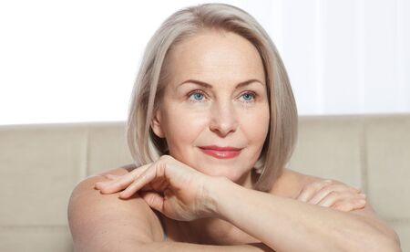 Fifty year old woman is very pleased with her well-groomed face. Plastic surgery collagen injections. Macro face. Selective focus on face. Realistic images with their own imperfections.の写真素材